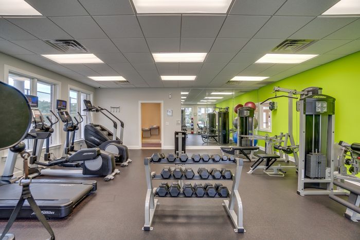 Modern fitness center featuring treadmills, weight racks, and diverse exercise equipment in a bright and inviting space.