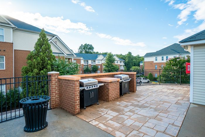 Inviting outdoor patio area with built-in brick grills and scenic view of apartment buildings.