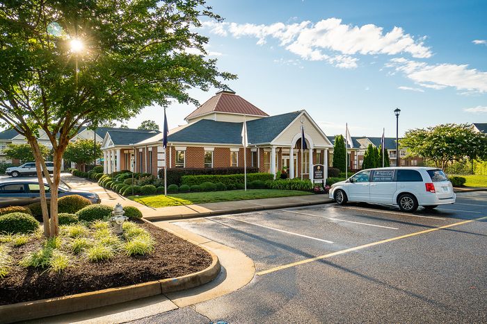 Sunny day view of a community building with classic brick architecture, surrounded by lush greenery.