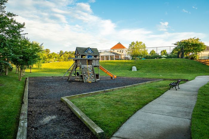 Beautifully landscaped playground with a wooden play structure and slide in a tranquil park setting.