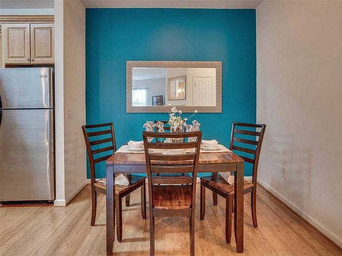 Inviting dining area with a wooden table, four chairs, and a blue accent wall.