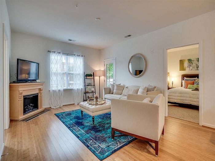 Bright living room with a modern fireplace, stylish seating area, and connecting bedroom view.