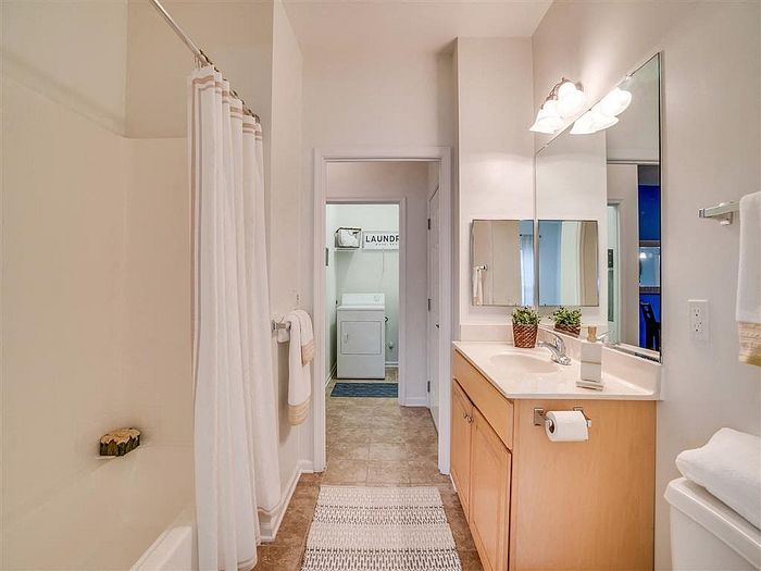 Modern bathroom with elegant vanity, mirror, and access to laundry area.