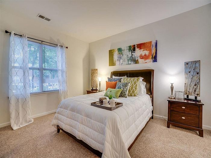Inviting bedroom with a plush bed adorned with vibrant accent pillows, soft lighting, and artistic decor.