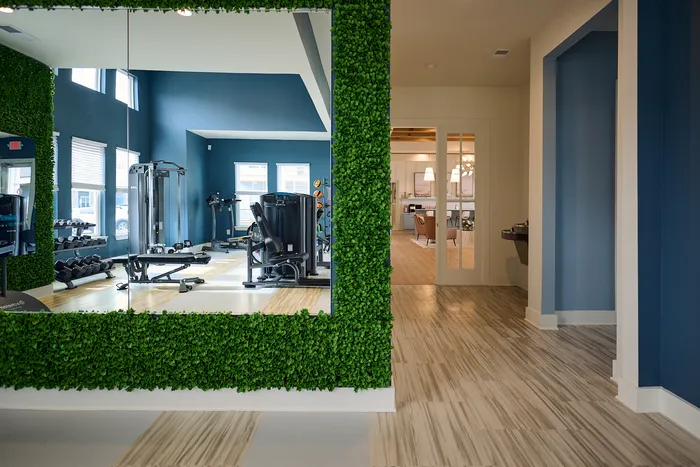 Bright gym with modern equipment and welcoming living room in elegant apartment complex.