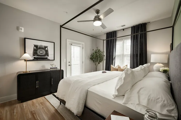 Chic bedroom featuring a stylish canopy bed, elegant decor, and a modern ceiling fan.