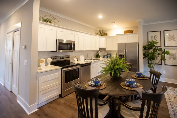 Modern kitchen and dining area featuring sleek white cabinetry, stainless steel appliances, and a stylish dining table set with blue dishware.