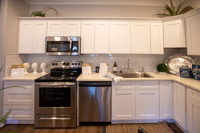 Modern kitchen with elegant white cabinetry, stainless steel appliances, and a sleek subway tile backsplash.