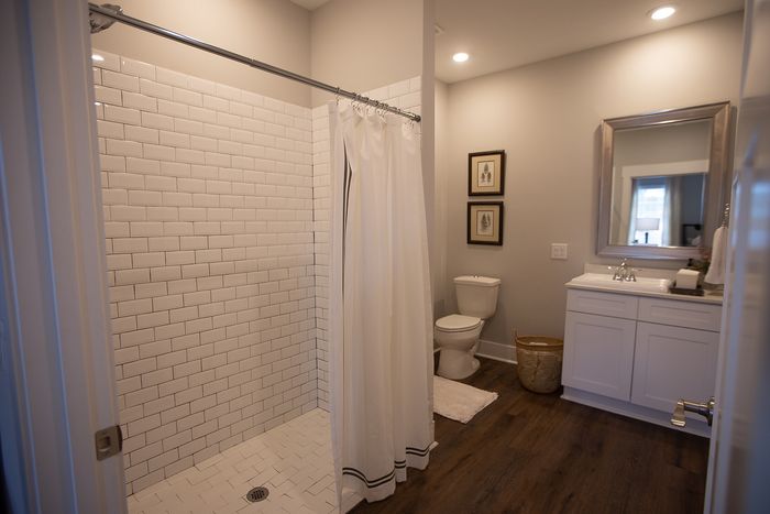Elegant modern bathroom with a spacious walk-in shower and classic subway tiling, featuring a sleek vanity and warm wood floors.