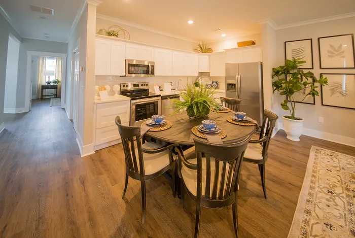 Warm and inviting kitchen with modern appliances, elegant dining table, hardwood floors, and vibrant greenery.