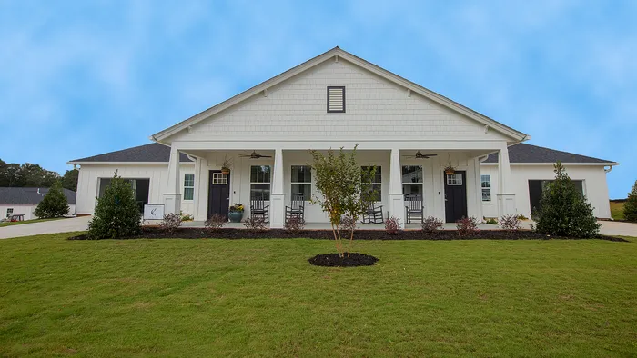 Charming suburban home with classic white facade, welcoming front porch, and lush green lawn under a clear blue sky.