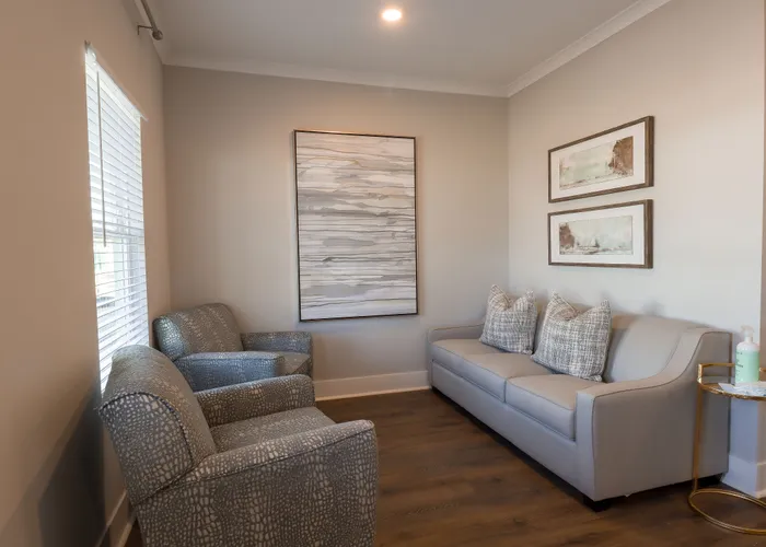 Inviting living room with elegant gray sofa, textured armchairs, and stylish wall art, perfect for relaxation.