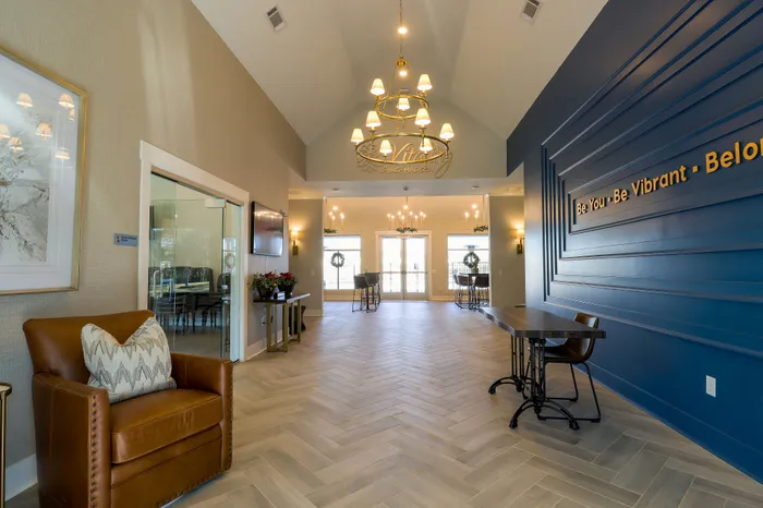 Elegant lobby with vaulted ceiling, luxurious leather chair, stylish chandelier, and modern decor for a welcoming atmosphere.
