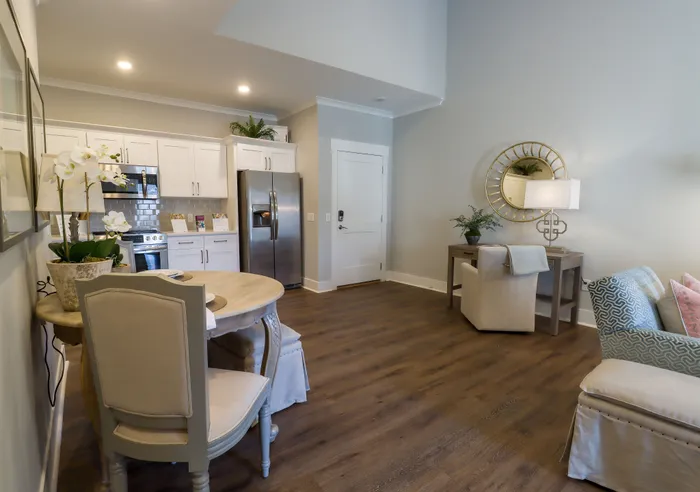 Elegant living area with open kitchen concept, featuring modern stainless steel appliances and cozy dining space, complemented by stylish decor and warm hardwood flooring.