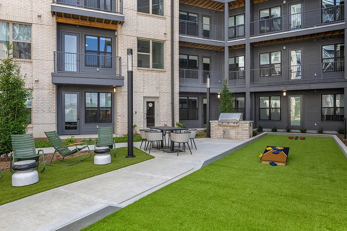 Inviting courtyard with modern patio furniture, outdoor grill, and lawn games offering a vibrant community space.