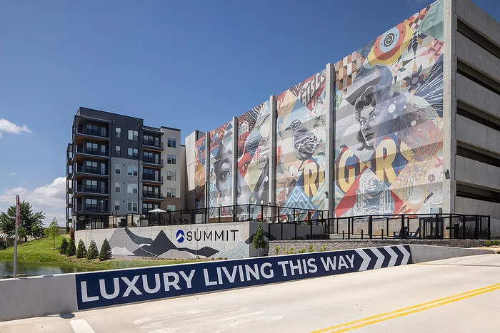 Contemporary apartment complex featuring vibrant street art and promoting luxury living in a modern urban setting.