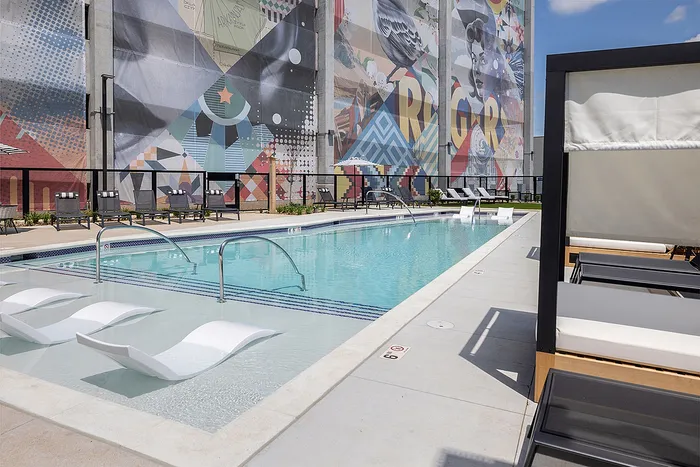 Vibrant apartment pool area with modern sun loungers and colorful mural backdrop.