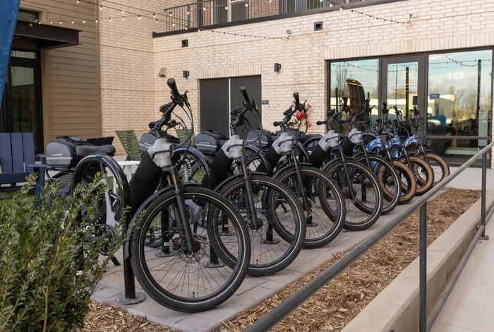 Modern urban apartment complex with a stylish fleet of electric bikes available for residents, promoting eco-friendly living.