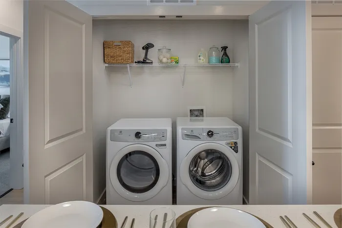 Modern laundry nook with sleek white washer and dryer, complemented by organized shelving for essentials.