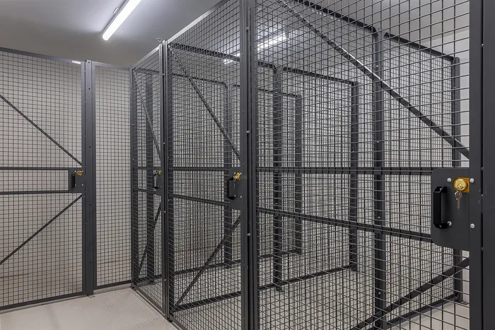 Secure and spacious storage cages with key lock in a well-lit area, ideal for storing belongings safely.