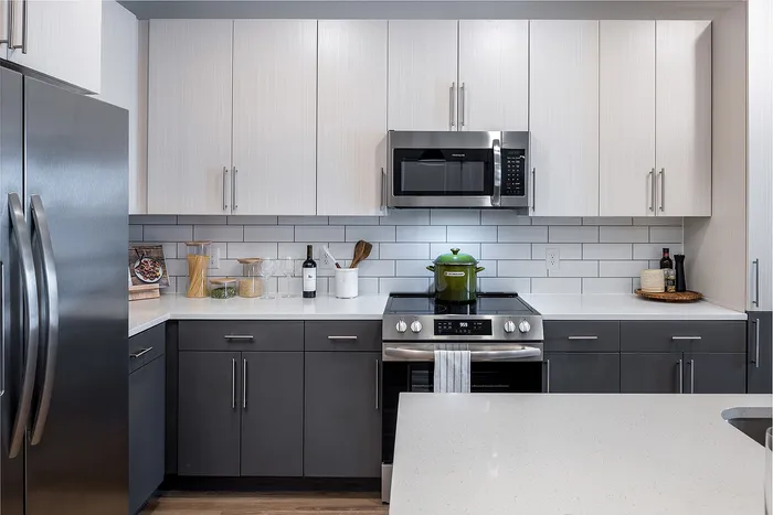 Modern kitchen with sleek gray cabinets, stainless steel appliances, and a pristine white countertop.