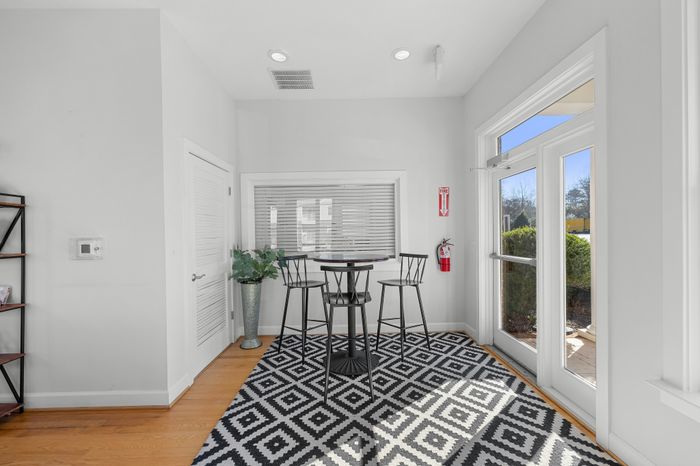 Bright, modern dining nook with a stylish bistro table, black chairs, vibrant geometric rug, and large windows offering abundant natural light.