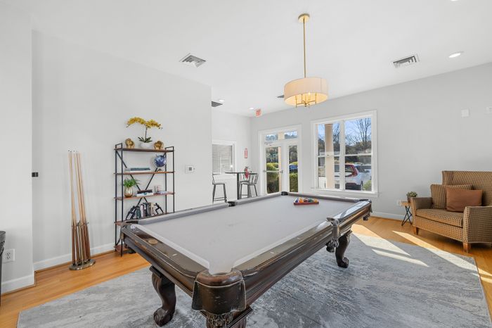 Bright and inviting recreational room featuring a stylish pool table, cozy seating, and natural light through large windows.