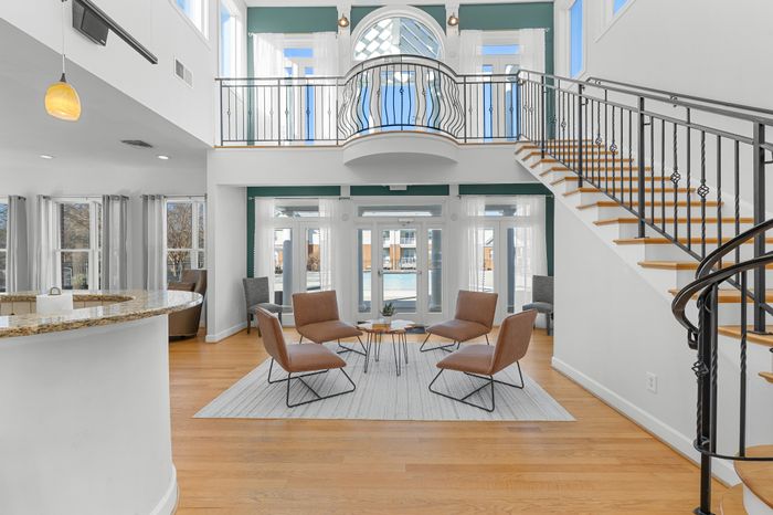 Elegant apartment with an open-concept living space, featuring a modern staircase, high ceilings, and abundant natural light through large windows.
