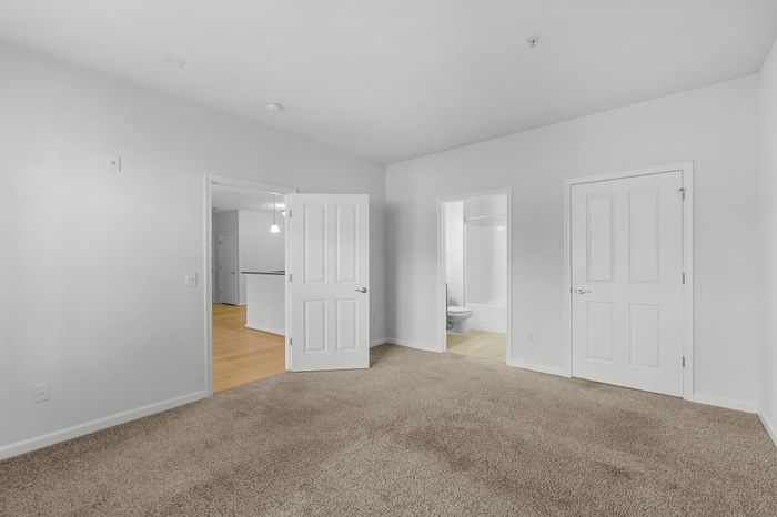 Bright, modern bedroom with plush carpet, en-suite bathroom, and open access to living area.