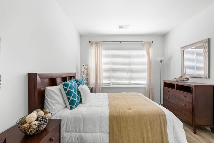 Charming bedroom with natural light, featuring elegant wood furniture, decorative pillows, and cozy ambiance.