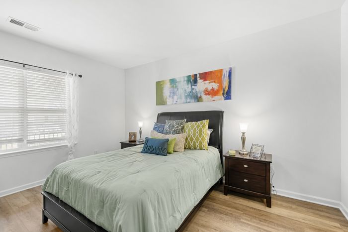 Inviting bedroom with stylish decor, featuring a cozy bed with colorful pillows, elegant nightstands, and vibrant abstract wall art, perfect for relaxation.