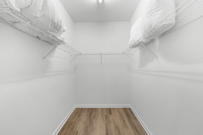 Spacious walk-in closet with elegant hardwood flooring and ample white shelving for organized storage.