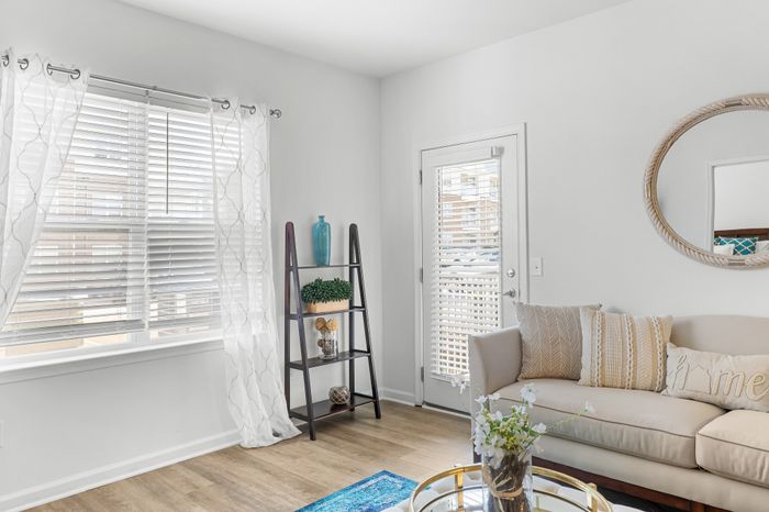 Elegant living room featuring chic decor, a comfortable sofa with decorative cushions, natural light streaming through sheer curtains, and stylish shelving.