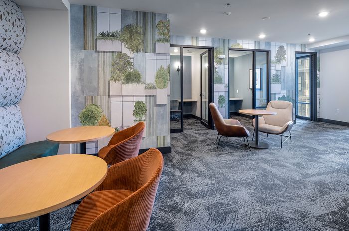 Modern apartment lobby with vibrant seating, artistic botanical wallpaper, and stylish lighting, offering a warm and inviting atmosphere.