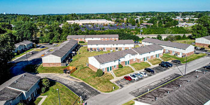Aerial view of a charming apartment community with well-maintained green spaces and convenient parking, nestled in a lush, scenic area.