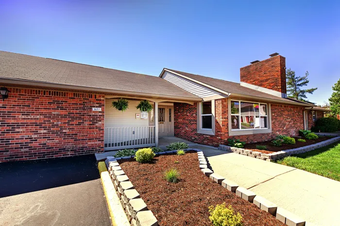 Charming brick-front home featuring a well-maintained garden, welcoming front entrance, and vibrant landscaping.