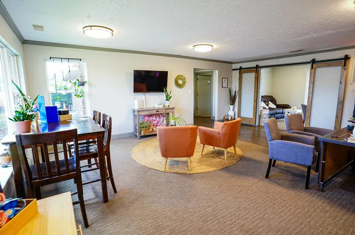 Bright and inviting living space with modern furnishings, featuring a cozy seating area, stylish rug, and large windows providing plenty of natural light.