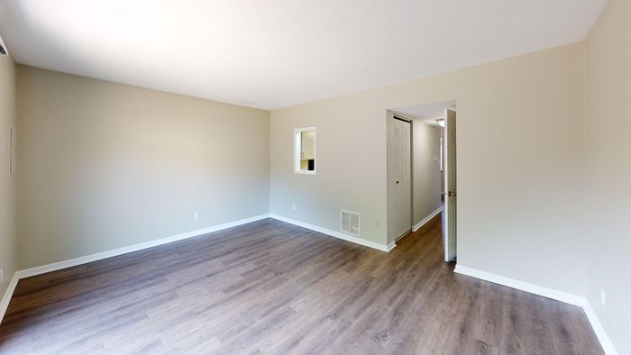 Bright and spacious living area with elegant hardwood floors, featuring a cozy window nook and sleek neutral walls.