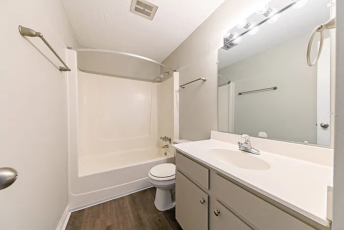 Bright, modern bathroom featuring a sleek vanity, a relaxing tub, and warm lighting on elegant wood flooring.