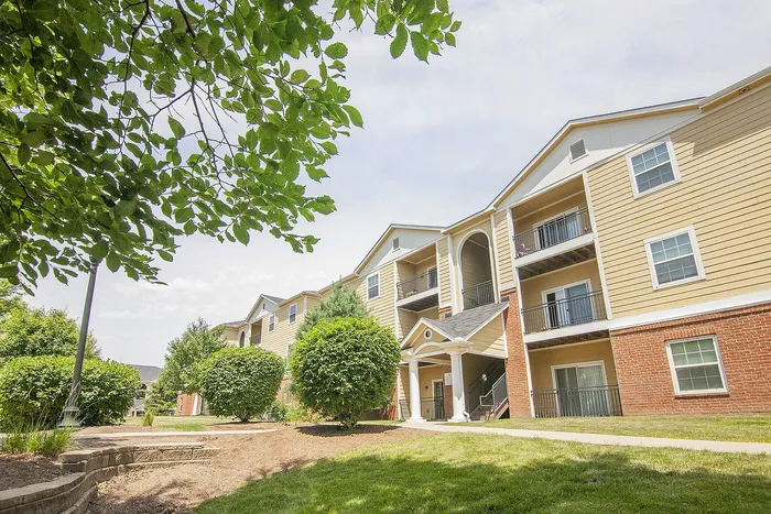 Charming apartment complex with modern balconies, lush greenery, and ample natural light.