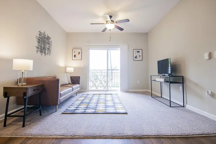 Bright, inviting living room featuring a chic leather sofa, contemporary decor, and a private balcony access.