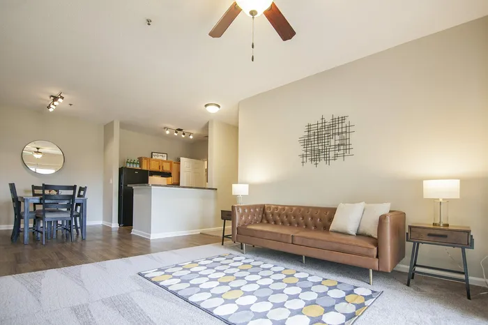 Modern open-plan living area with elegant sofa, stylish dining table set, and contemporary kitchen in a bright, spacious apartment.