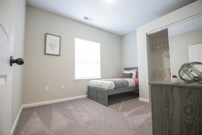 Bright and cozy bedroom with a comfortable single bed, stylish decor, and ample closet space, creating a modern and inviting atmosphere.