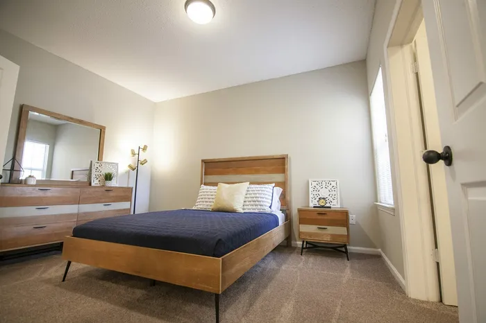 Inviting bedroom with modern wooden furniture, plush bedding, and ample natural light for a cozy ambiance.
