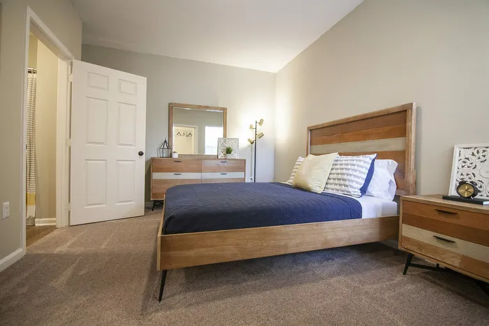 Cozy and modern bedroom with a wooden bed frame, stylish dresser, and warm lighting creating a serene atmosphere.