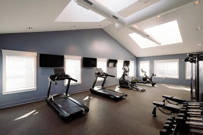 Bright, modern fitness center featuring state-of-the-art treadmills, elliptical machines, and a variety of free weights. Enjoy your workout in a spacious, skylit room with natural light.