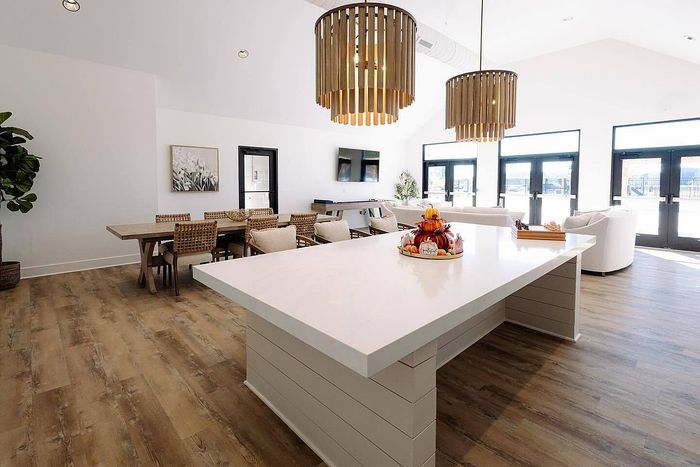 Bright and stylish open-plan living area featuring a modern kitchen island, elegant dining set, and chic lighting fixtures, perfect for entertaining.