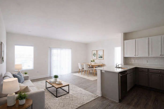 Bright and modern open-plan living area with cozy sofa, elegant dining table, and sleek kitchen offering ample natural light.