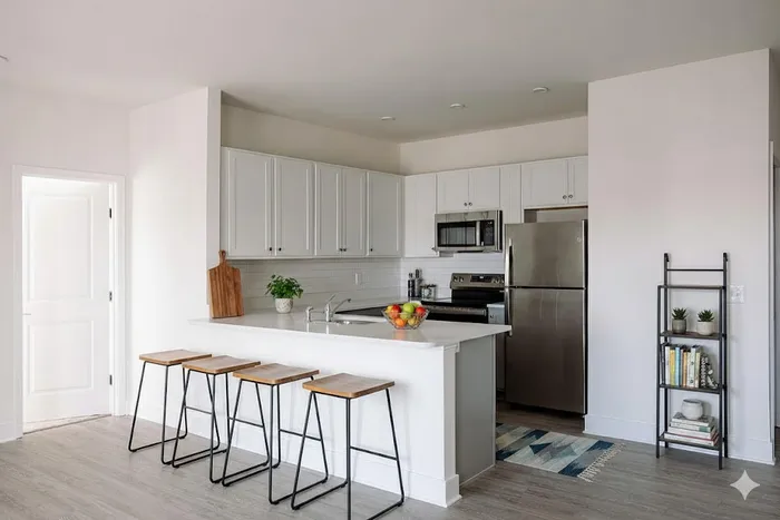Chic modern kitchen with stainless steel appliances, white cabinetry, and a sleek island with stylish bar stools.