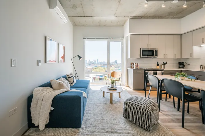 1 Bedroom Student Apartments in Lincoln Park, Chicago, IL | Post Chicago | Living Room Featuring Large Windows with Natural Sunlight and High Ceilings with Exposed Concrete